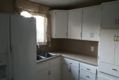 Original kitchen with worn cabinets and laminate counters before remodel